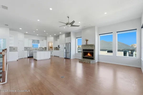 an empty room with wooden floor fan and windows