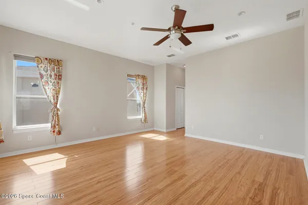a view of an empty room with wooden floor and a window