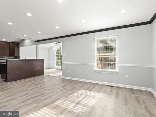 a view of an empty room with a window and a kitchen