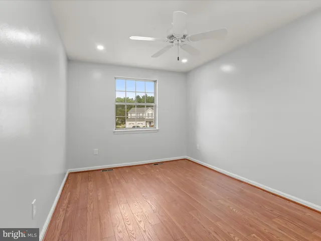an empty room with windows and ceiling fan
