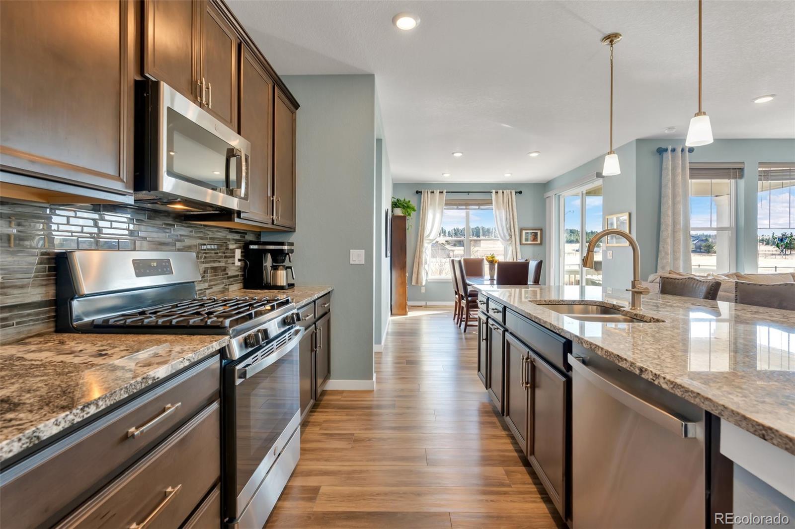 1122 Highpoint Trail Elizabeth, CO 80107 - Photo 15 of 45 a kitchen with stainless steel appliances granite countertop a stove top oven a sink dishwasher a dining table and chairs with wooden floor