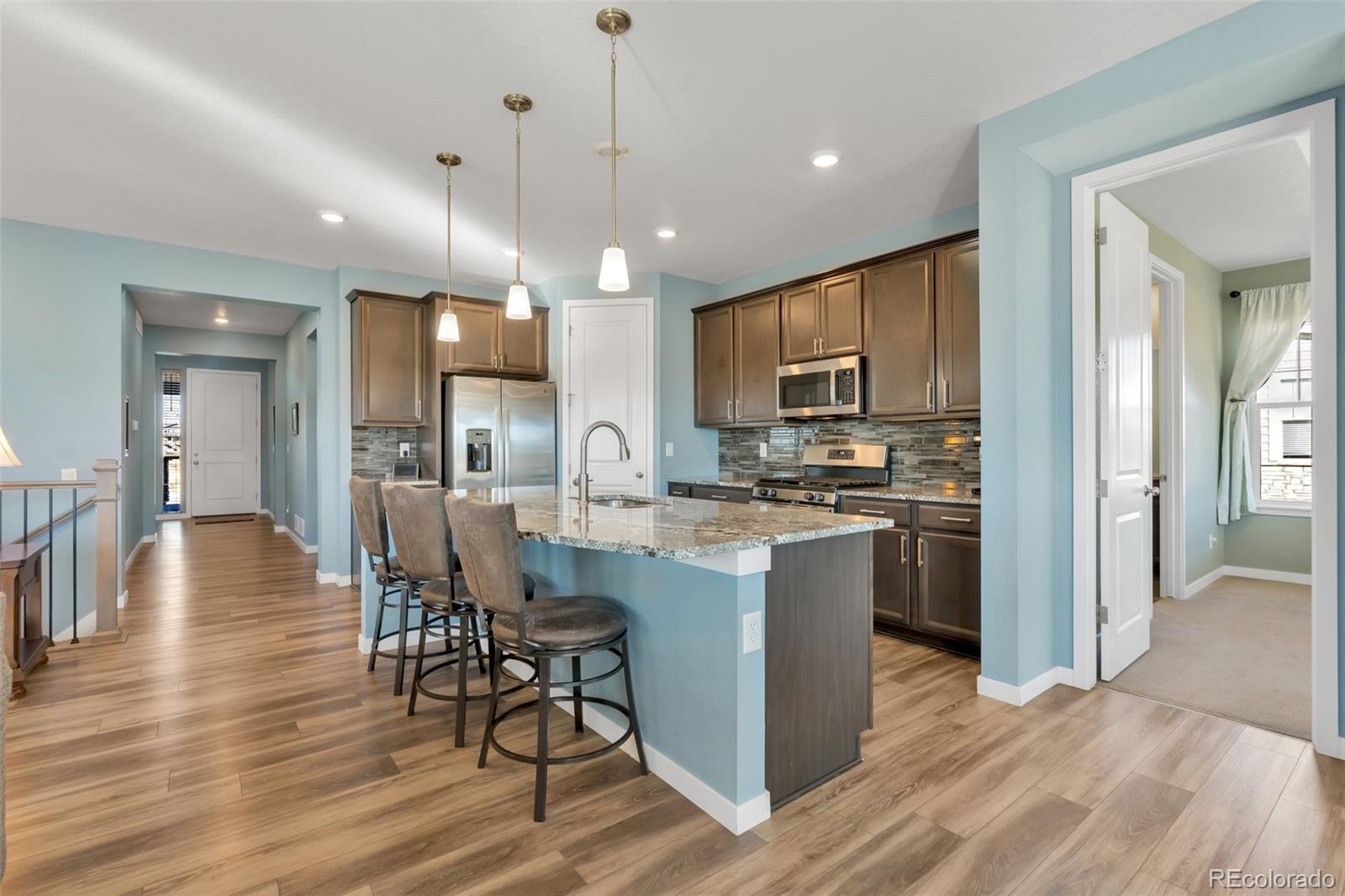1122 Highpoint Trail Elizabeth, CO 80107 - Photo 23 of 45 a kitchen with stainless steel appliances kitchen island granite countertop a refrigerator a stove a sink a dining table and chairs with wooden floor