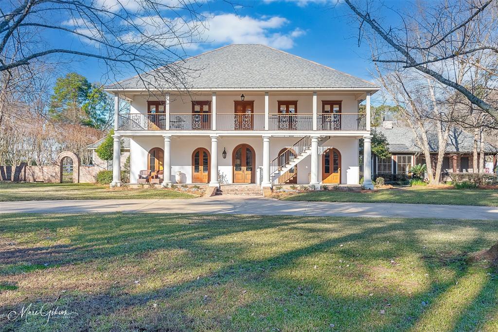 View of front of home featuring a front yard, a porch, and a balcony