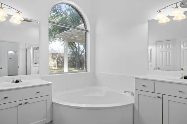 a spacious bathroom with a tub sink shower and mirror