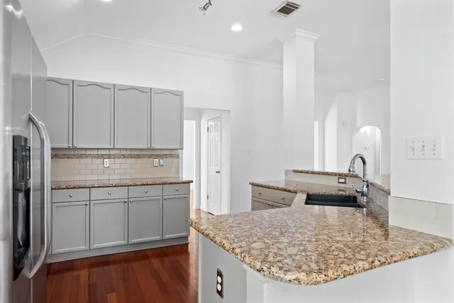 a view of a kitchen and an empty room with wooden floor and a kitchen