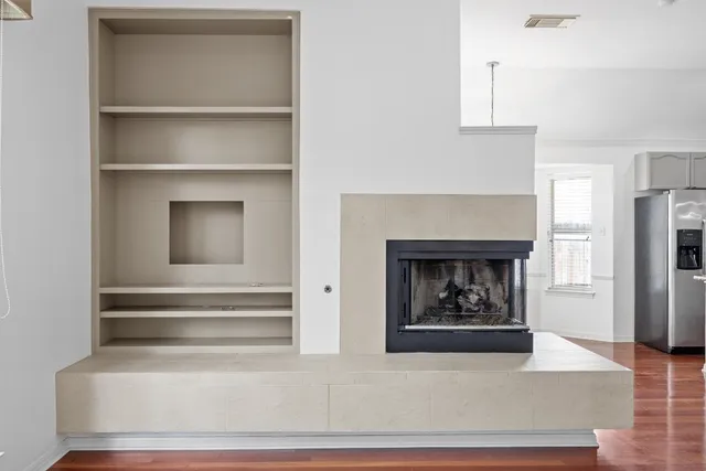 a view of an empty room with a window and wooden floor