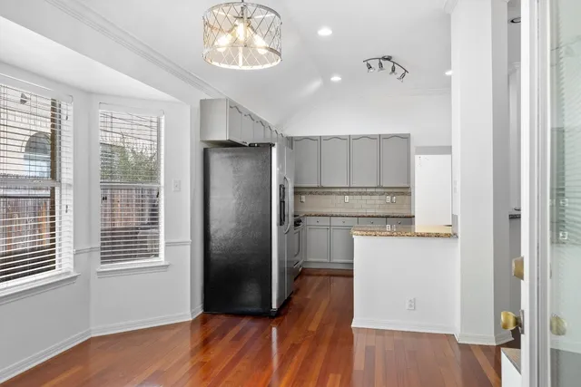 an empty room with wooden floor mirror and windows