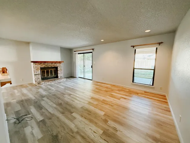 a view of an empty room with a fireplace and a window