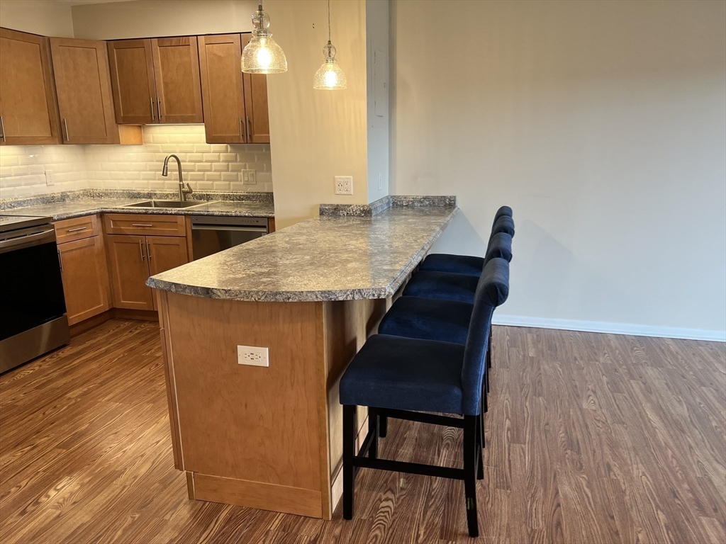 1006 Paradise Road, Unit 3R Swampscott, MA 01907 - Photo 5 of 34 a kitchen with stainless steel appliances kitchen island granite countertop wooden cabinets a sink a stove and dishwasher with wooden floor