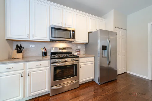 a kitchen with stainless steel appliances white cabinets and a stove a refrigerator with wooden floor