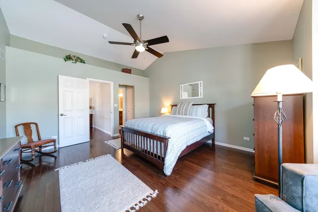 a bedroom with a bed a dresser and wooden floor