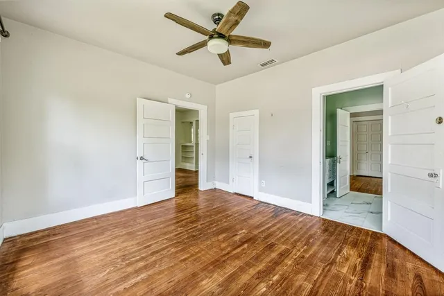 a view of a room with wooden floor and a ceiling fan