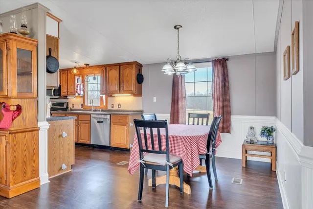 a kitchen with stainless steel appliances granite countertop a refrigerator a sink dishwasher and wooden cabinets with wooden floor