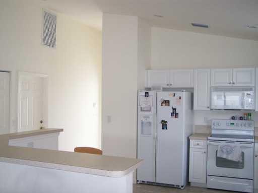 2434 Southwest Malibu Way Stuart, FL 34997 - Photo 3 of 8 a kitchen with stainless steel appliances white cabinets and a refrigerator