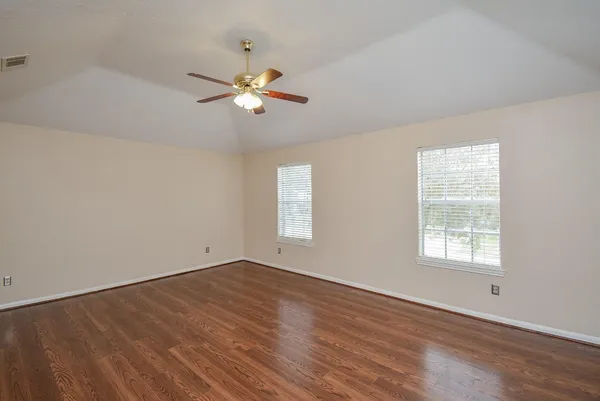 a view of empty room with wooden floor and fan