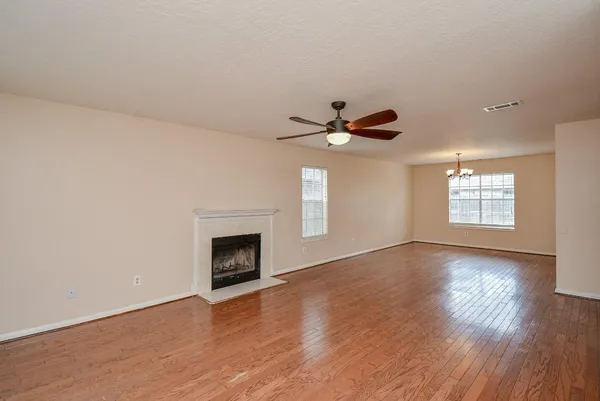an empty room with wooden floor fireplace and windows
