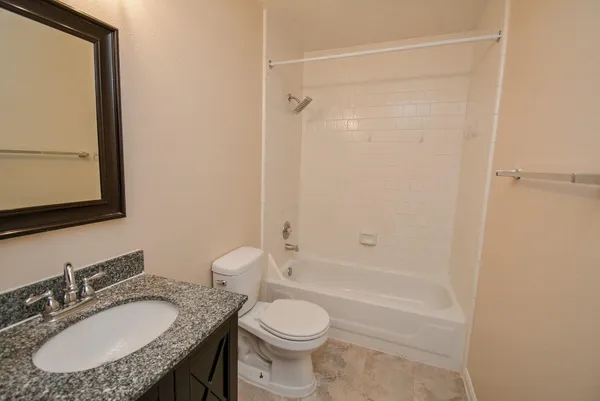 a bathroom with a granite countertop sink toilet a mirror and shower