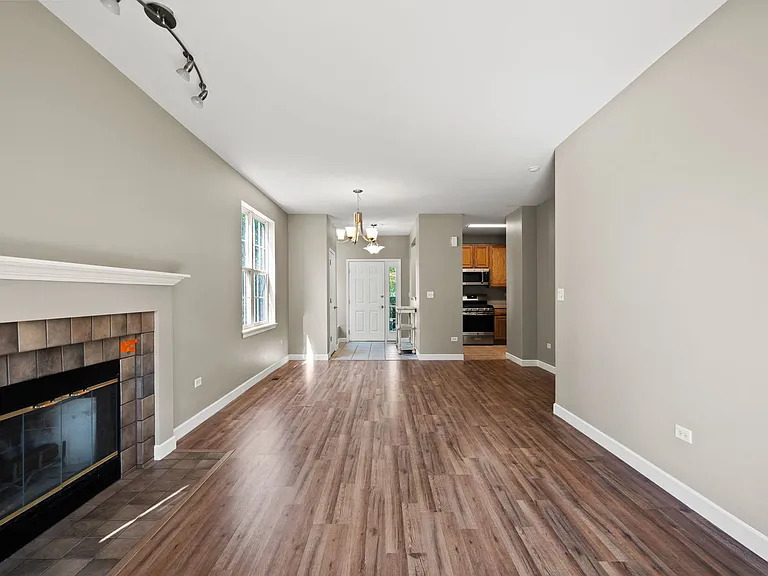 2568 Golf Ridge Circle, Unit 2568 Naperville, IL 60563 - Photo 5 of 18 a view of an empty room with wooden floor fireplace and a window