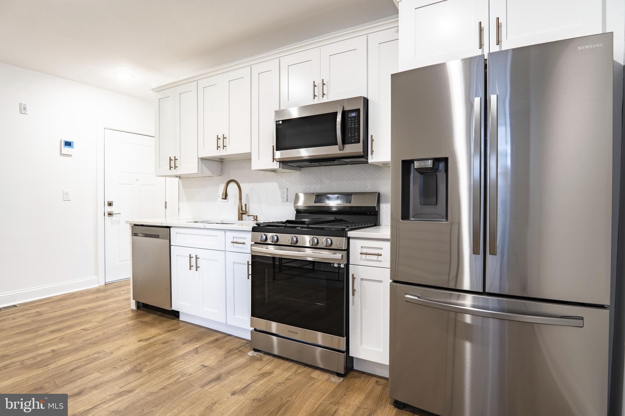 a kitchen with stainless steel appliances a refrigerator a stove top oven a sink and cabinets