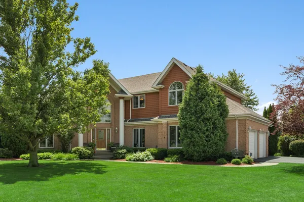 a front view of a house with a yard and trees