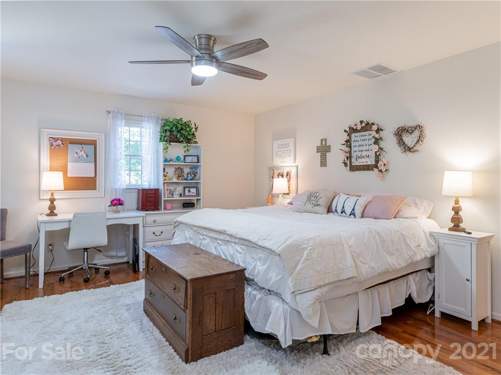 103 Windsong Drive Fairview, NC 28730 - Photo 22 of 36 a spacious bedroom with a bed a table and a chandelier