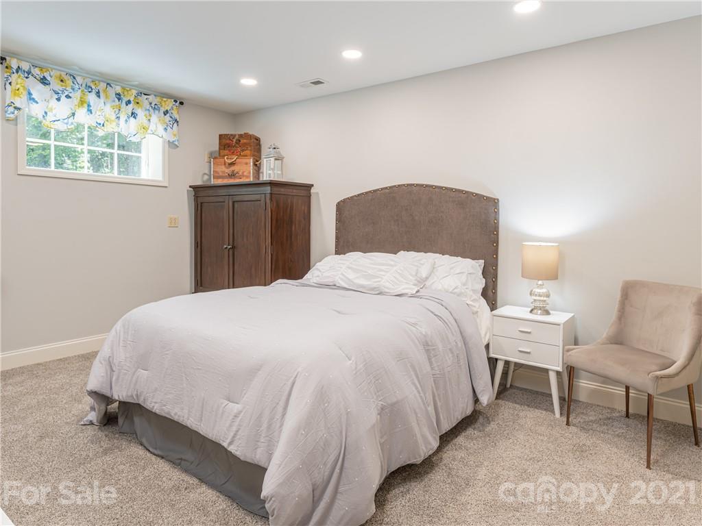 103 Windsong Drive Fairview, NC 28730 - Photo 27 of 36 a spacious bedroom with a bed and a chair