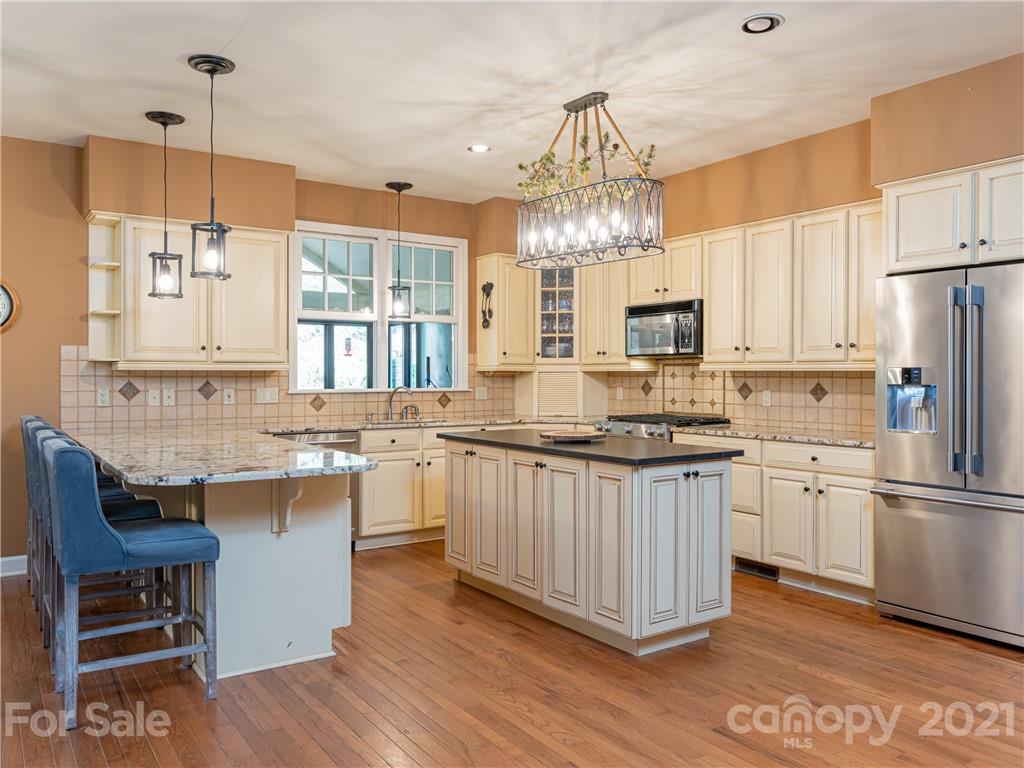 103 Windsong Drive Fairview, NC 28730 - Photo 10 of 36 a kitchen with granite countertop a sink cabinets stainless steel appliances and a chandelier