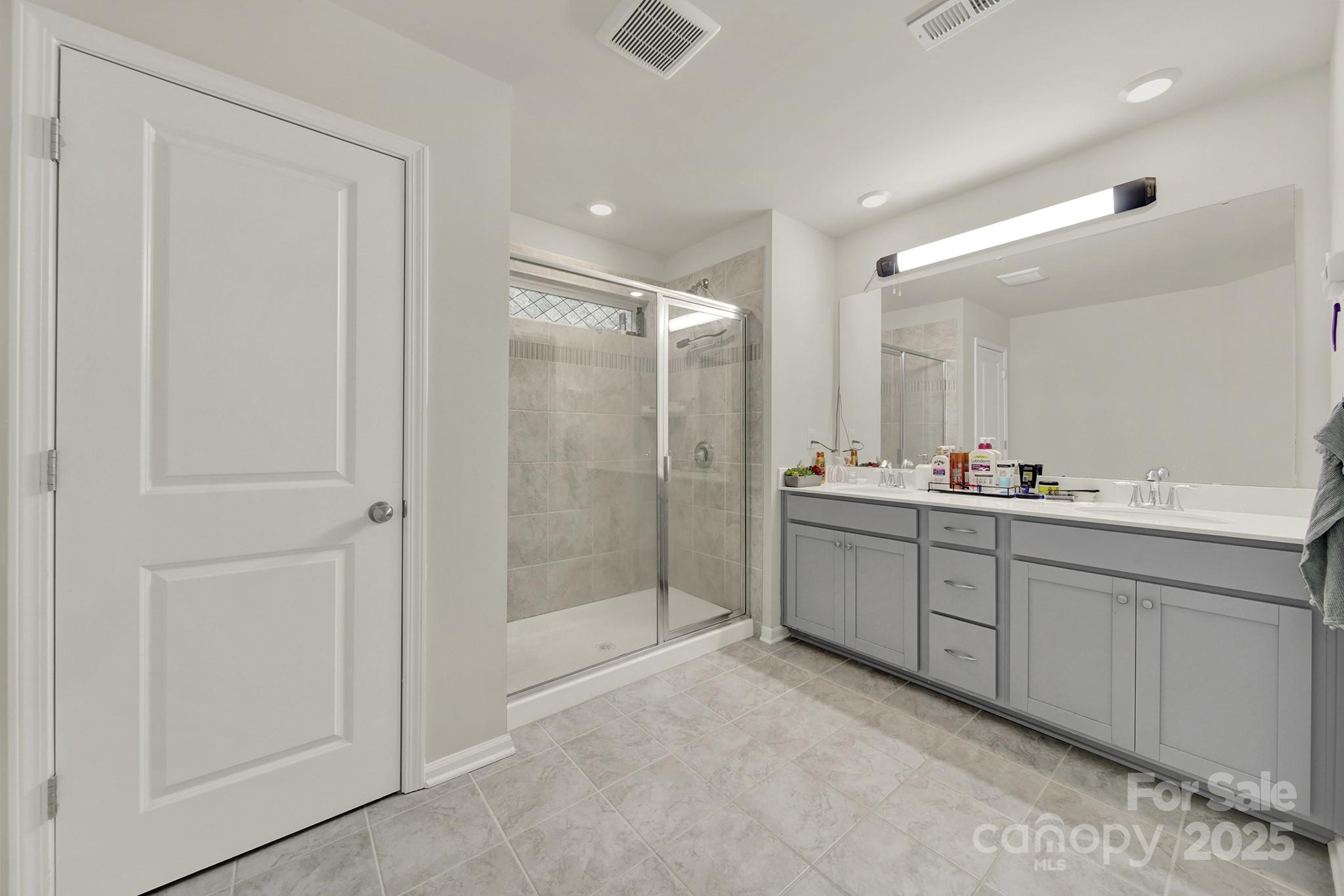 6009 Chelsea Oaks Ridge Fort Mill, SC 29708 - Photo 25 of 30 a bathroom with a mirror a double vanity sink and shower
