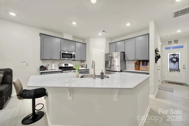 a large kitchen with stainless steel appliances granite countertop a stove a sink a refrigerator a microwave and white cabinets