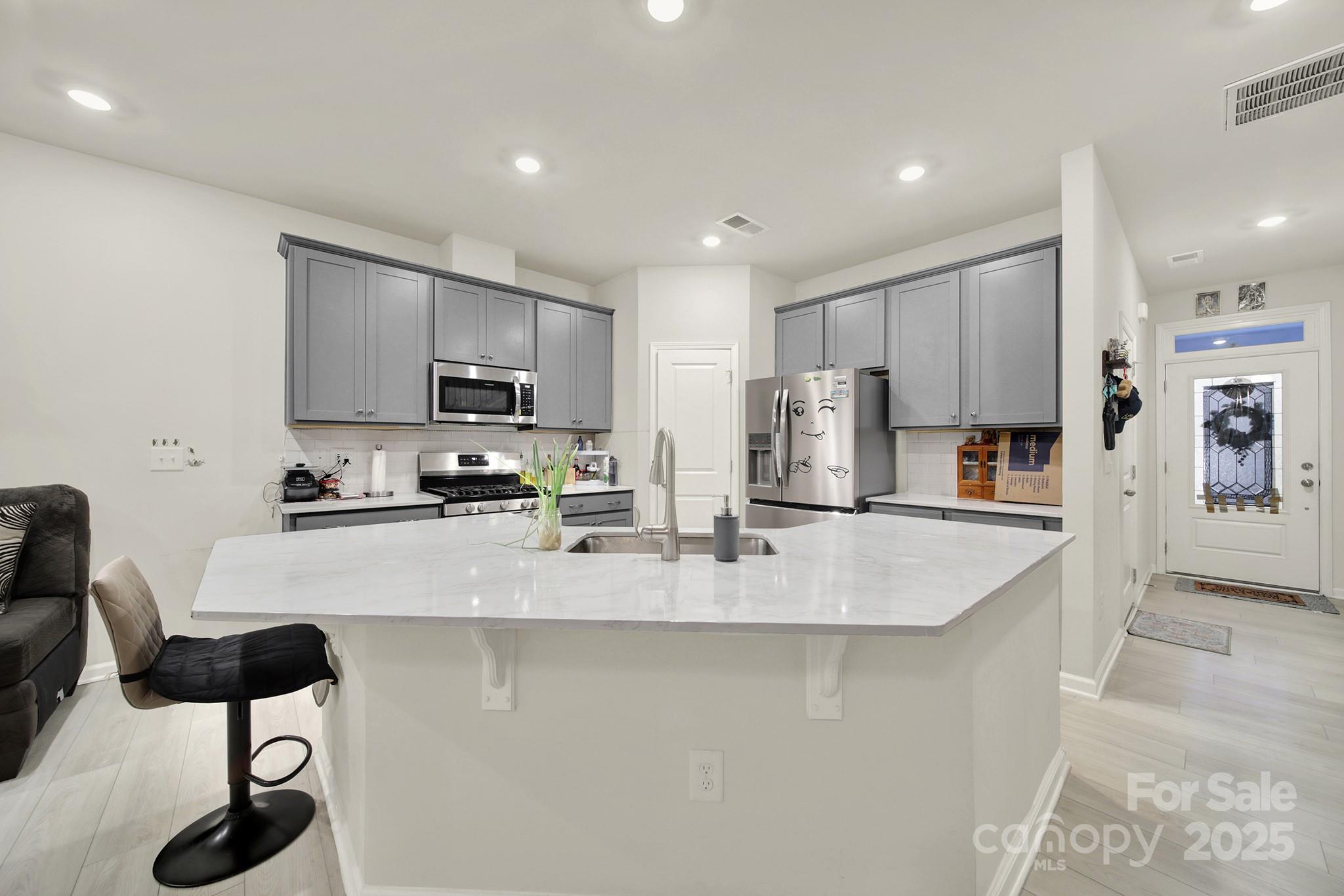 6009 Chelsea Oaks Ridge Fort Mill, SC 29708 - Photo 5 of 30 a large kitchen with stainless steel appliances granite countertop a stove a sink a refrigerator a microwave and white cabinets