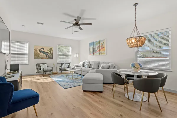 a kitchen with stainless steel appliances kitchen island granite countertop a stove a refrigerator a oven a sink with a dining table and chairs with wooden floor