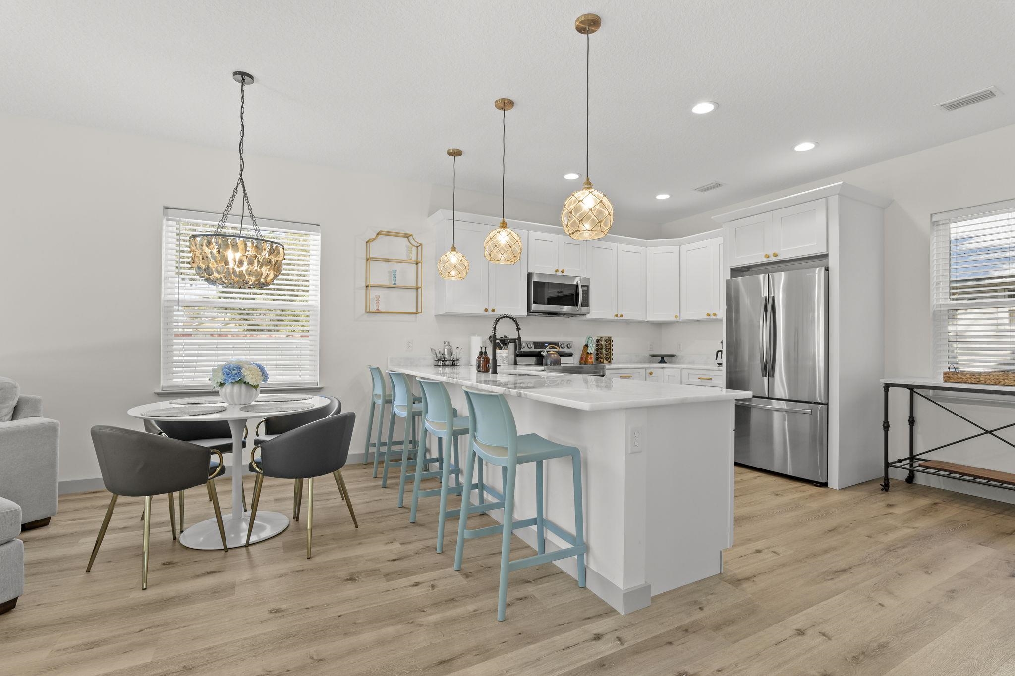 110 Moore Street St. Augustine, FL 32084 - Photo 3 of 39 a kitchen with stainless steel appliances kitchen island granite countertop a stove a refrigerator a oven a sink with a dining table and chairs with wooden floor