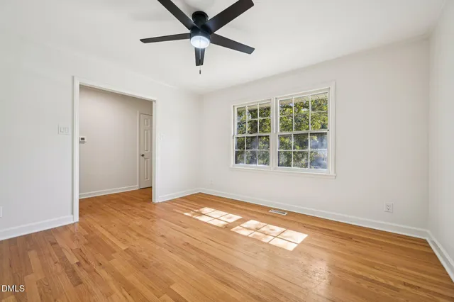 a view of an empty room with window and wooden floor
