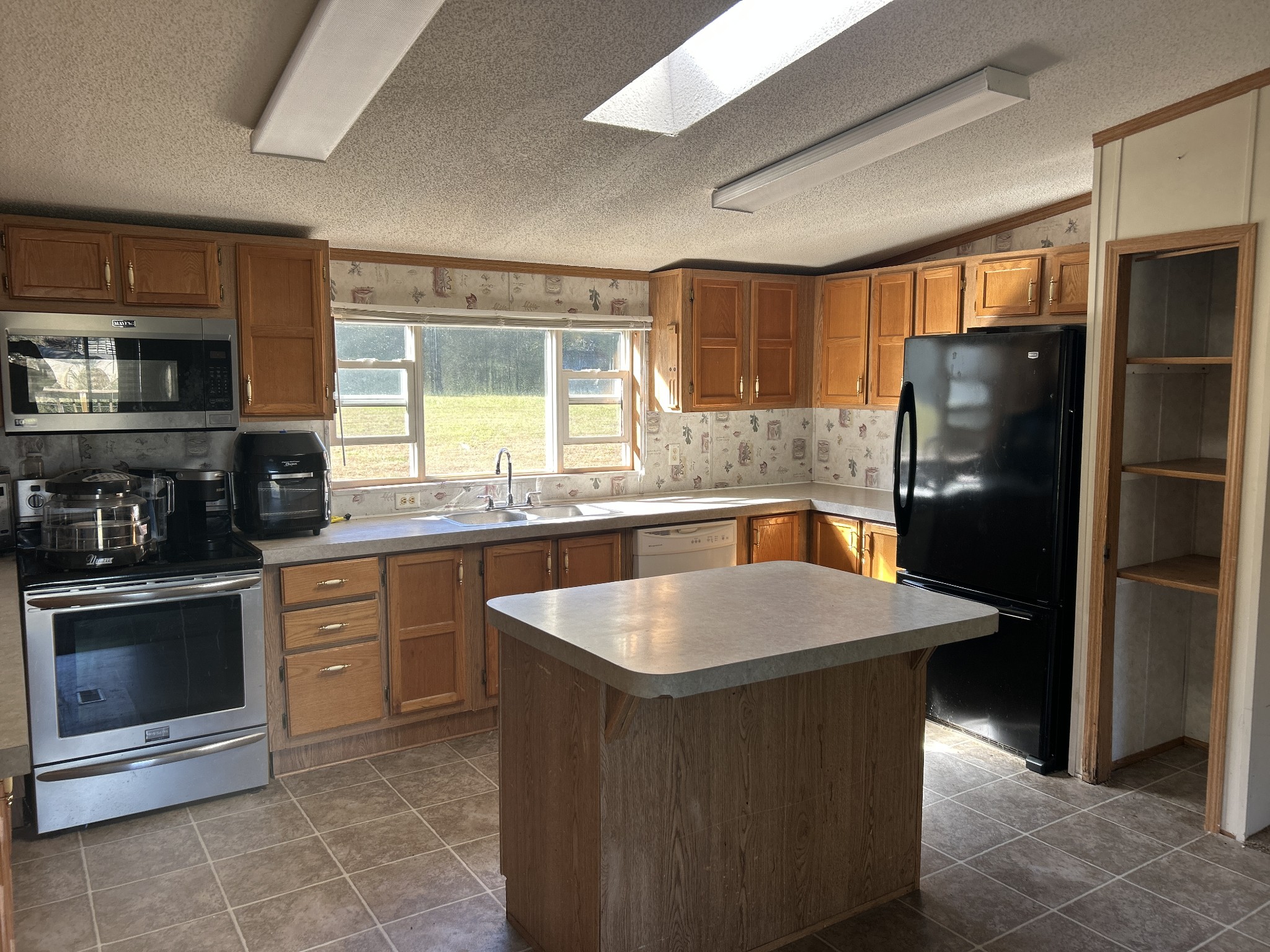 784 Garrison Road Hohenwald, TN 38462 - Photo 7 of 36 a kitchen with stainless steel appliances granite countertop a sink stove and refrigerator