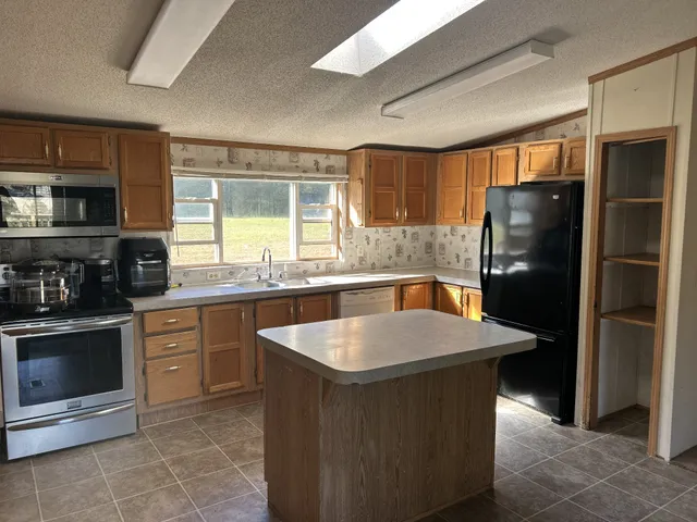 a kitchen with stainless steel appliances kitchen island granite countertop a refrigerator and a sink