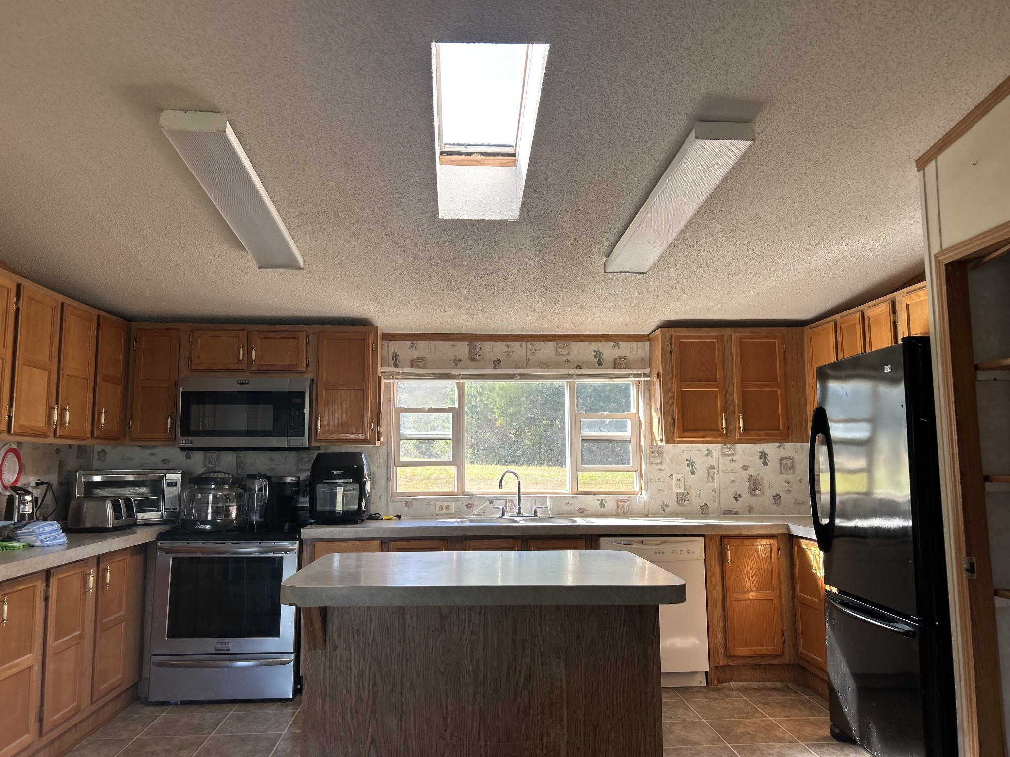 784 Garrison Road Hohenwald, TN 38462 - Photo 10 of 36 a kitchen with stainless steel appliances granite countertop a stove a sink dishwasher a refrigerator and a microwave oven
