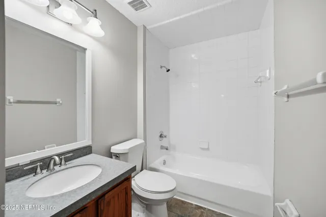 a bathroom with a granite countertop sink a toilet a mirror and a bathtub