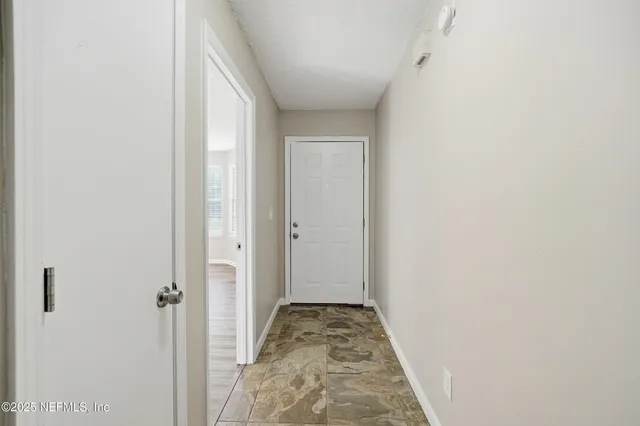a view of a hallway with wooden floor and a bathroom
