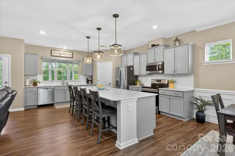 a kitchen with kitchen island granite countertop wooden floors and white appliances