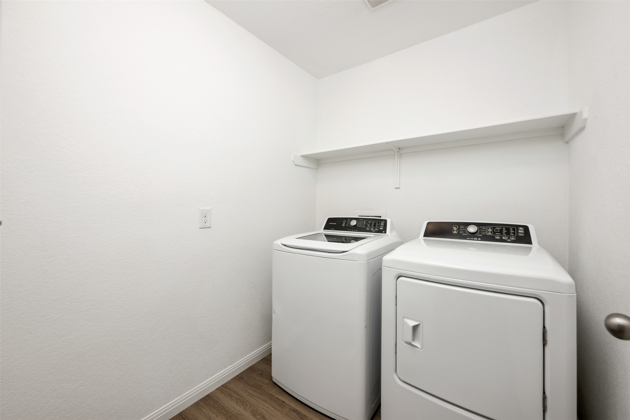 14900 Retha Pass Austin, TX 78725 - Photo 25 of 39 Dedicated laundry space featuring wood-finish flooring, white walls, and a built-in storage shelf