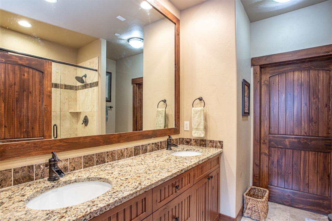 421 Rainbow Drive, Unit 5 Silverthorne, CO 80498 - Photo 22 of 36 a bathroom with a granite countertop sink a mirror and a shower