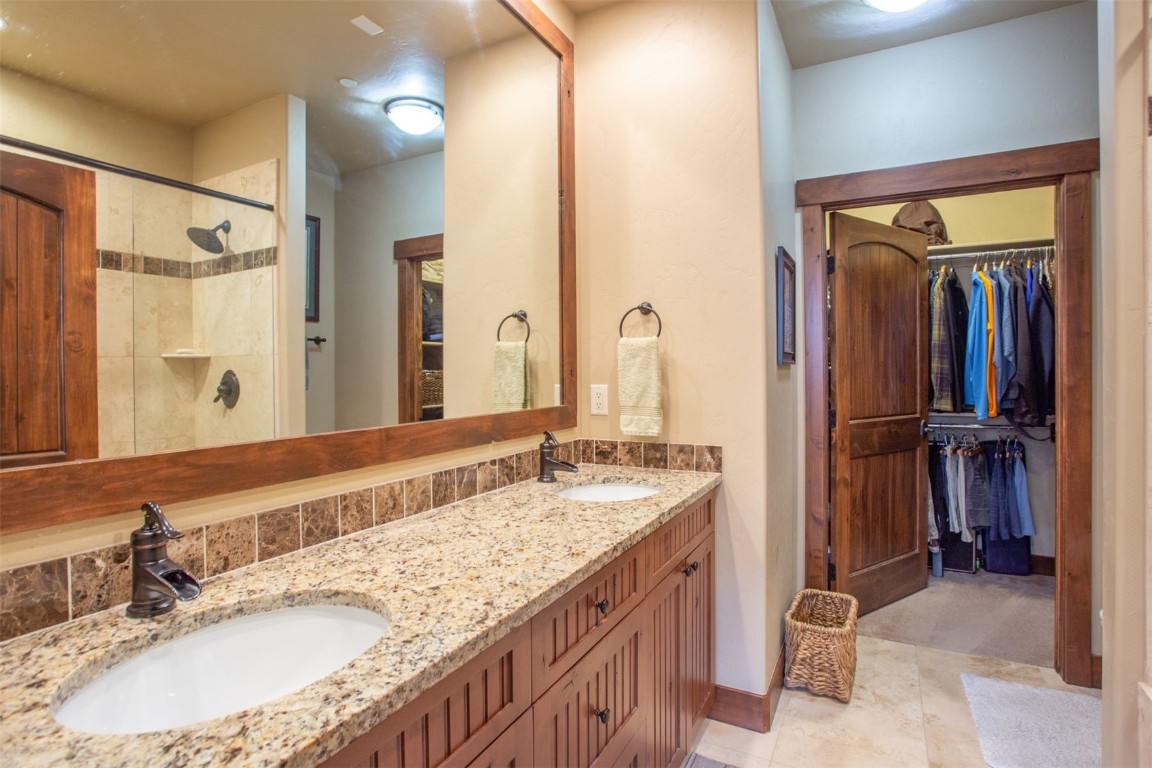 421 Rainbow Drive, Unit 5 Silverthorne, CO 80498 - Photo 23 of 36 a bathroom with a granite countertop sink a mirror and a shower