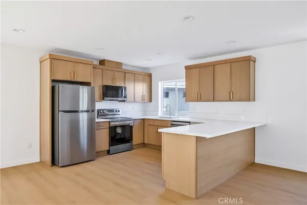 a kitchen with stainless steel appliances granite countertop a refrigerator a stove top oven a sink dishwasher and wooden cabinets