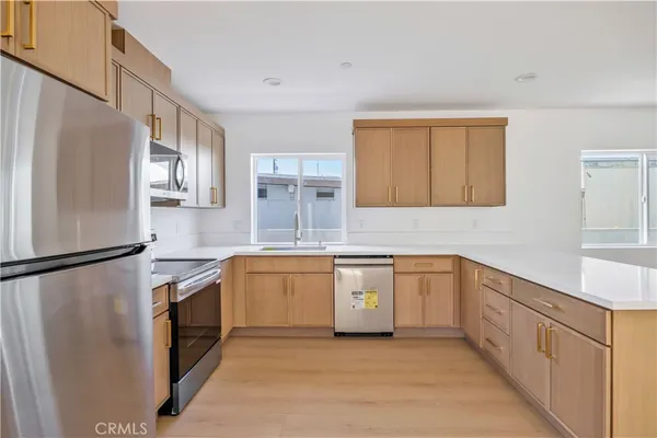 a kitchen with granite countertop stainless steel appliances a refrigerator a sink and white cabinets