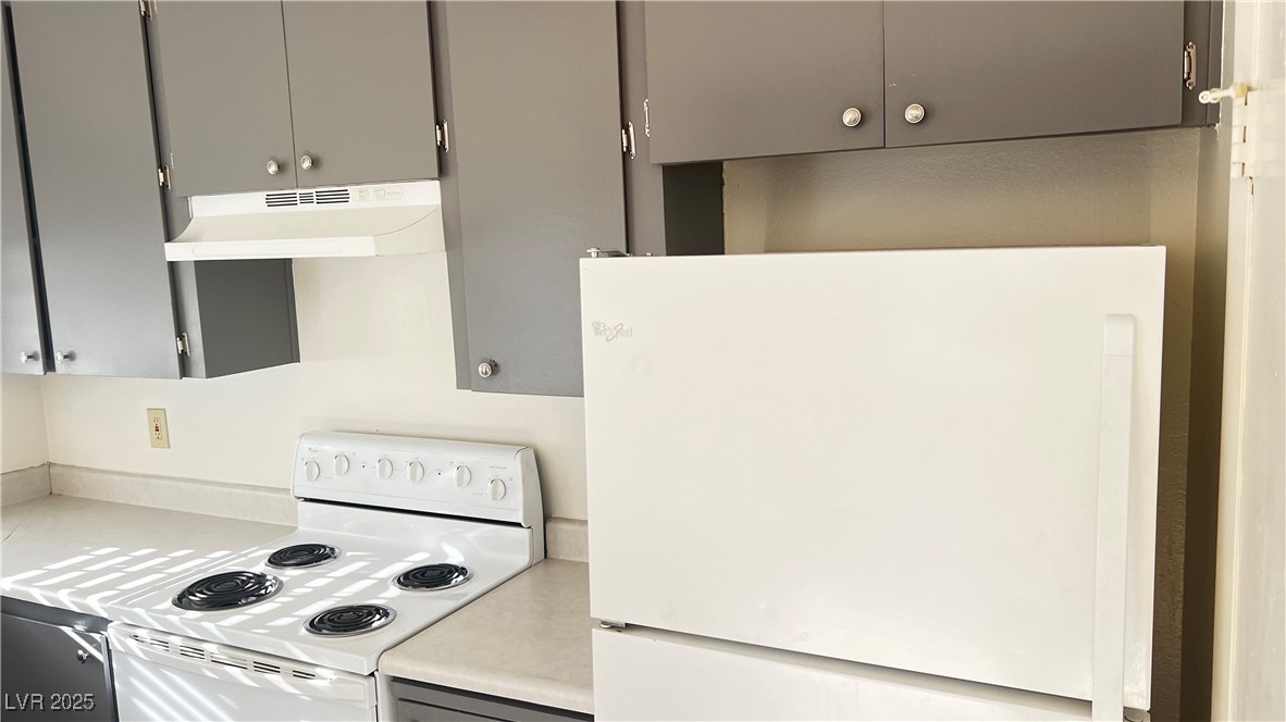 1486 Elizabeth Avenue, Unit 1 Las Vegas, NV 89119 - Photo 19 of 34 Kitchen with white appliances, light countertops, under cabinet range hood, and gray cabinets
