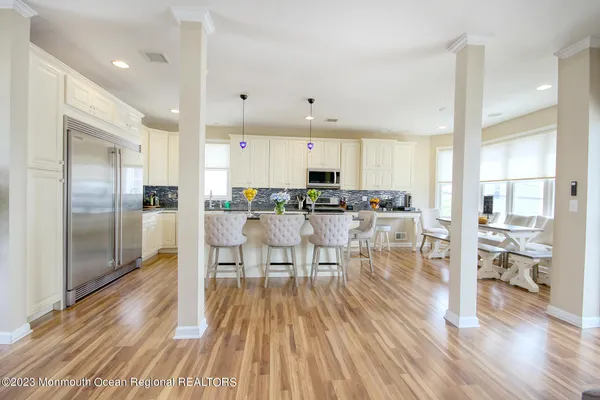 a view of a kitchen with kitchen island stainless steel appliances wooden floor and a view of living room