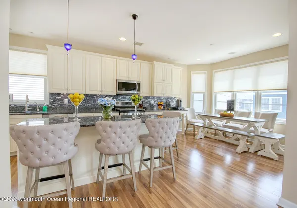 a kitchen with stainless steel appliances granite countertop a stove a sink a refrigerator a dining table and chairs with wooden floor