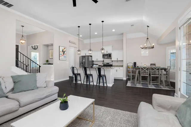 a living room with furniture kitchen view and a wooden floor