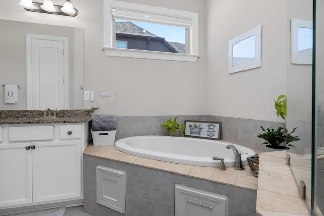 a bathroom with a granite countertop sink and a bathtub