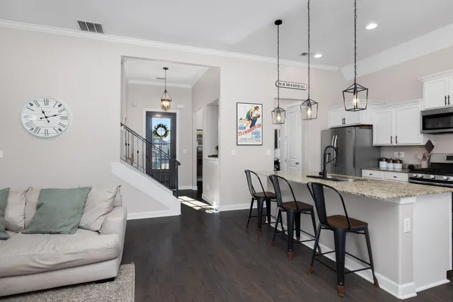 a living room with furniture kitchen view and a wooden floor